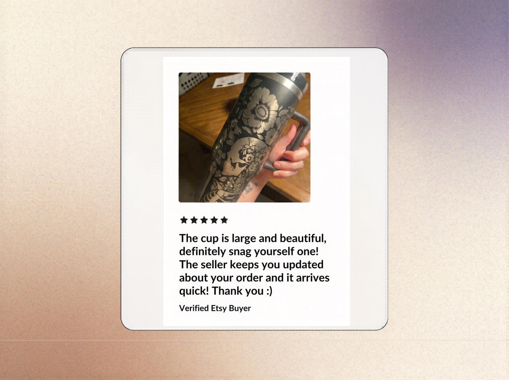 May include: A large, black tumbler with intricate floral and skull engravings. The tumbler has a handle and a silver lid. The design is etched into the metal, creating a detailed, contrasting pattern.